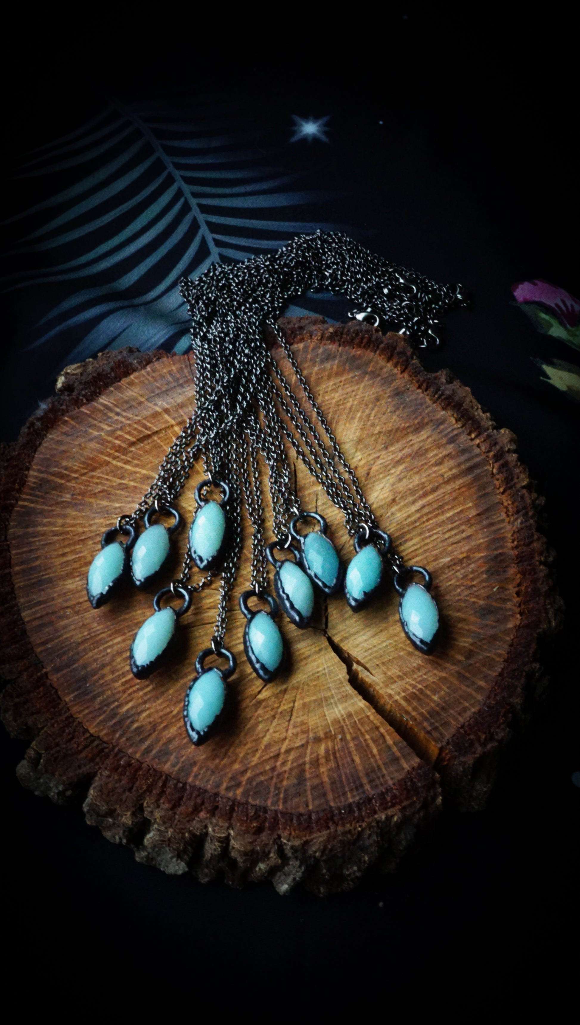 Necklace with light blue stones on a wooden block against a dark background