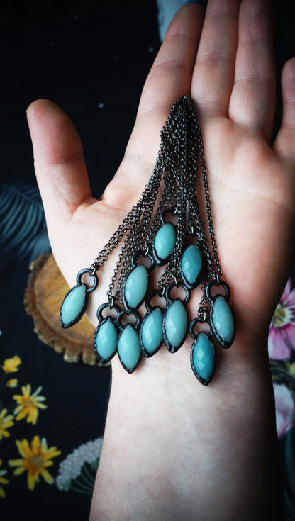 light blue and black small pendants hanging in hand