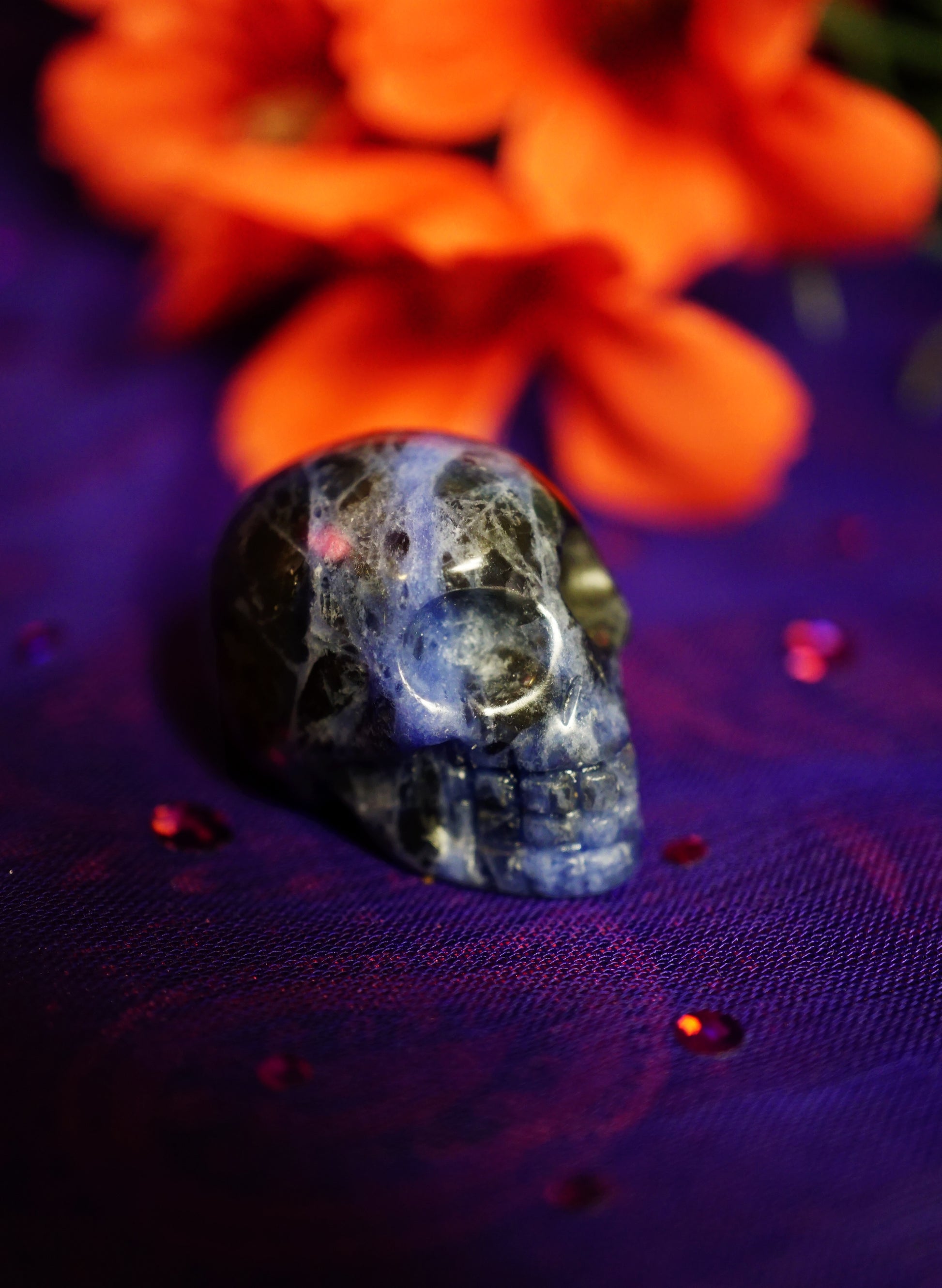 Crystal skull on a purple fabric with orange flowers in the background