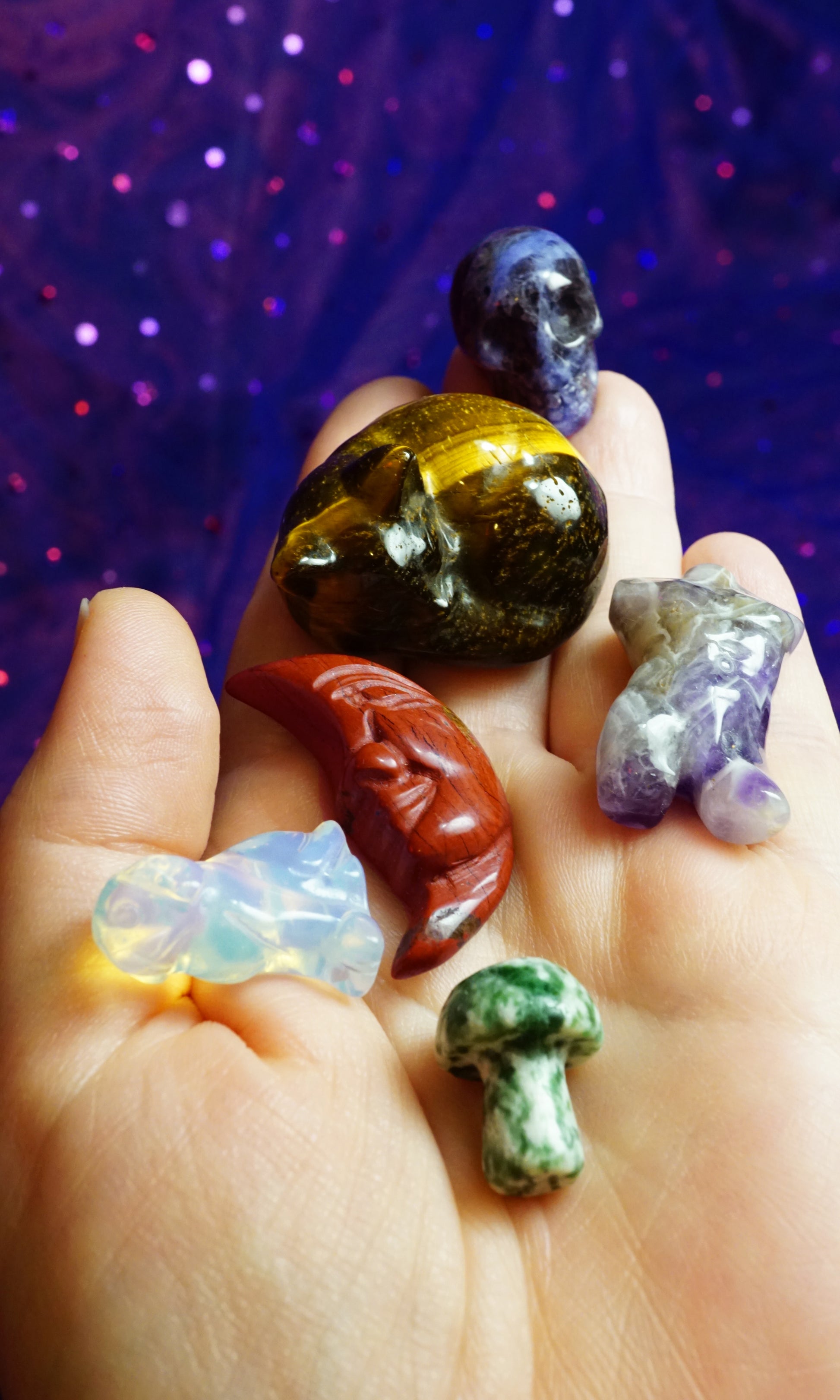 Hand holding various colorful crystals against a purple glittery background