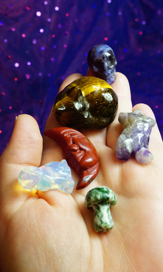 Hand holding various colorful crystals against a purple glittery background