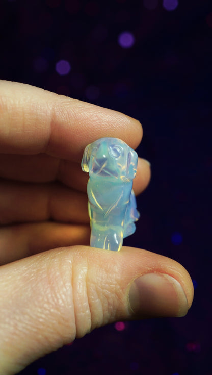 Opalite doggy figurine held between fingers against a dark background