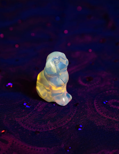 Opalite glass dog figurine on a dark purple textured surface