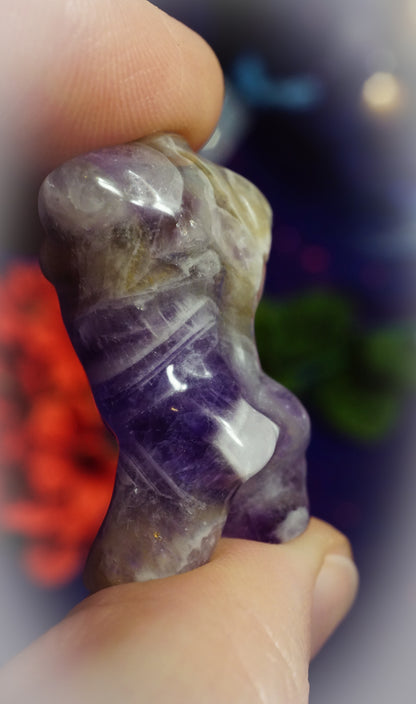 Amethyst crystal held between fingers with a blurred background