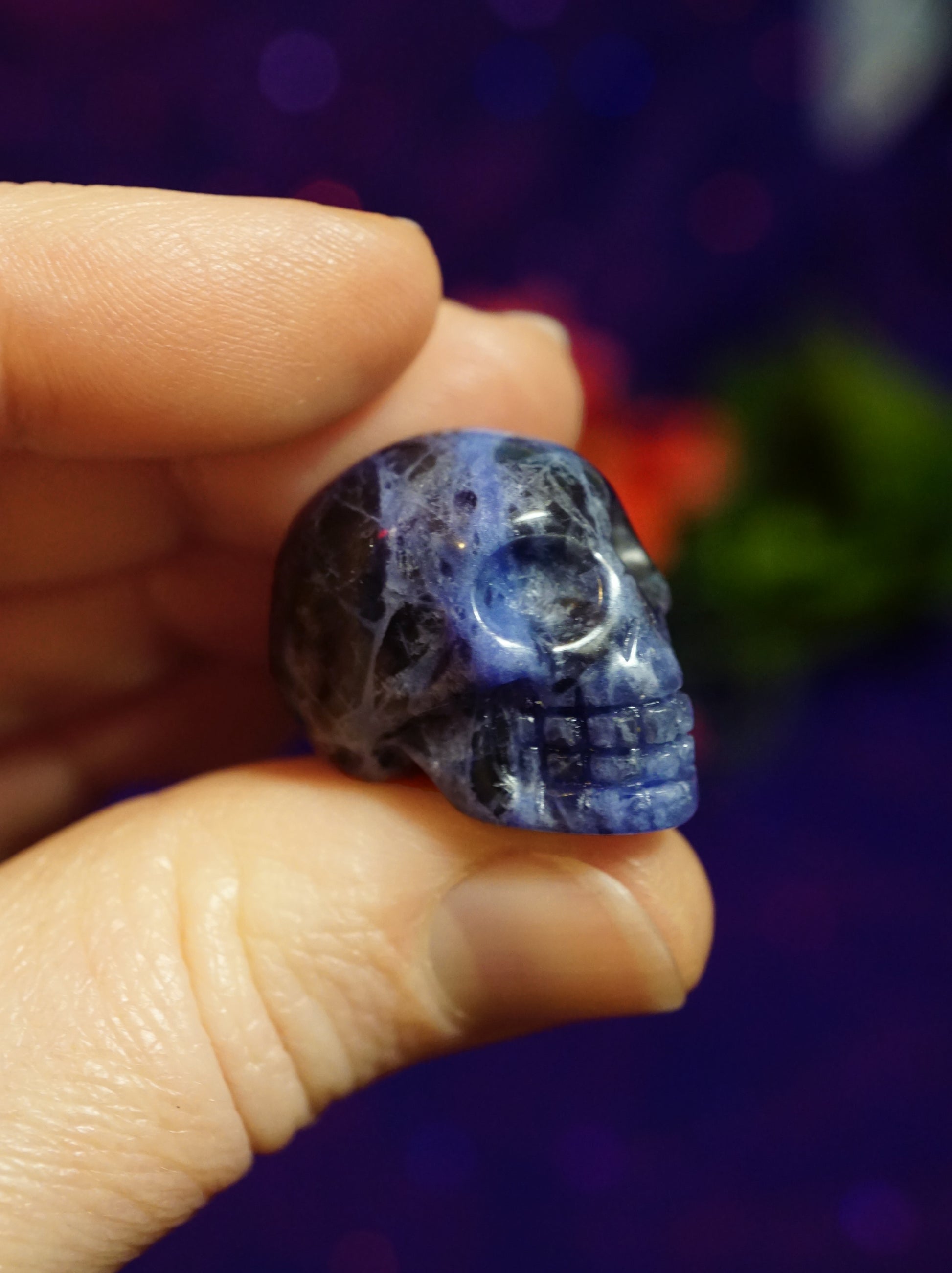 Hand holding a blue crystal skull against a blurred background