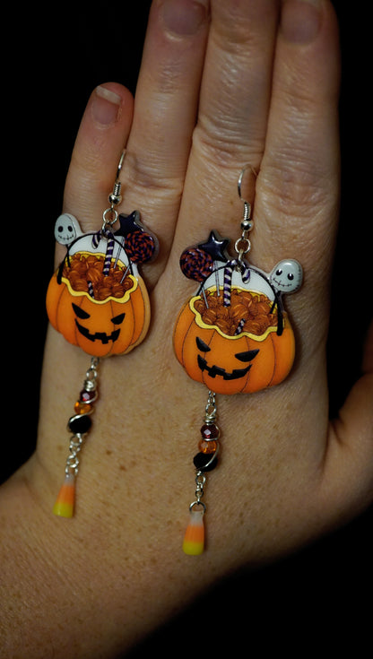 Halloween-themed pumpkin dangles on a hand against a dark background