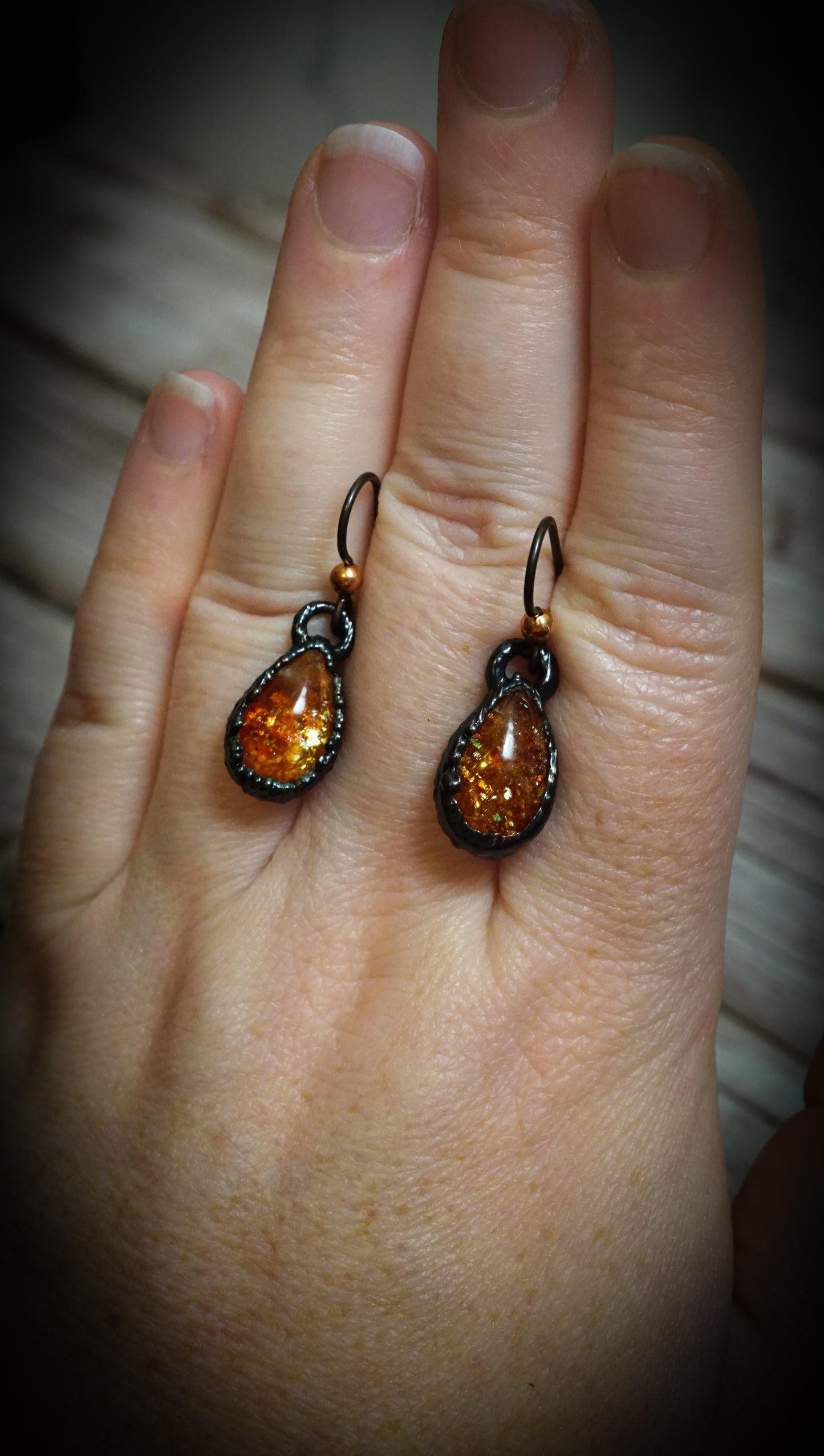 richly colored orange sunstone earrings on hand