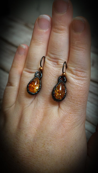 richly colored orange sunstone earrings on hand