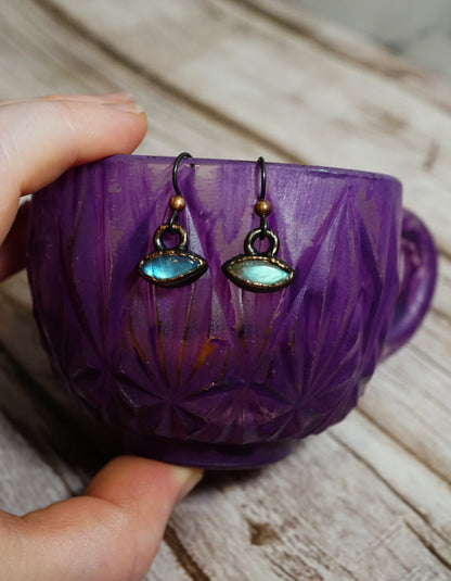 Purple cup with earrings hanging inside on a wooden surface