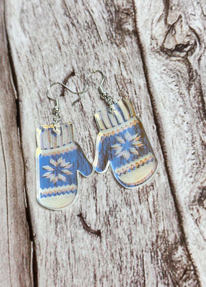 Pair of earrings shaped like mittens with blue and white patterns on a wooden surface.