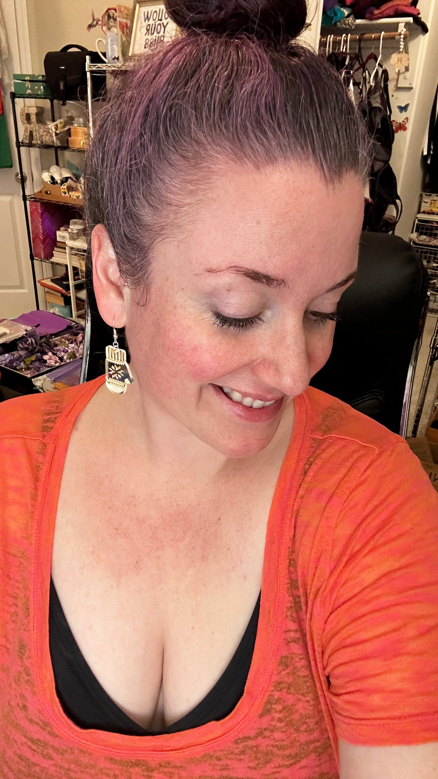 beautiful woman wearing mitten earrings and and orange shirt. woman has purple hair