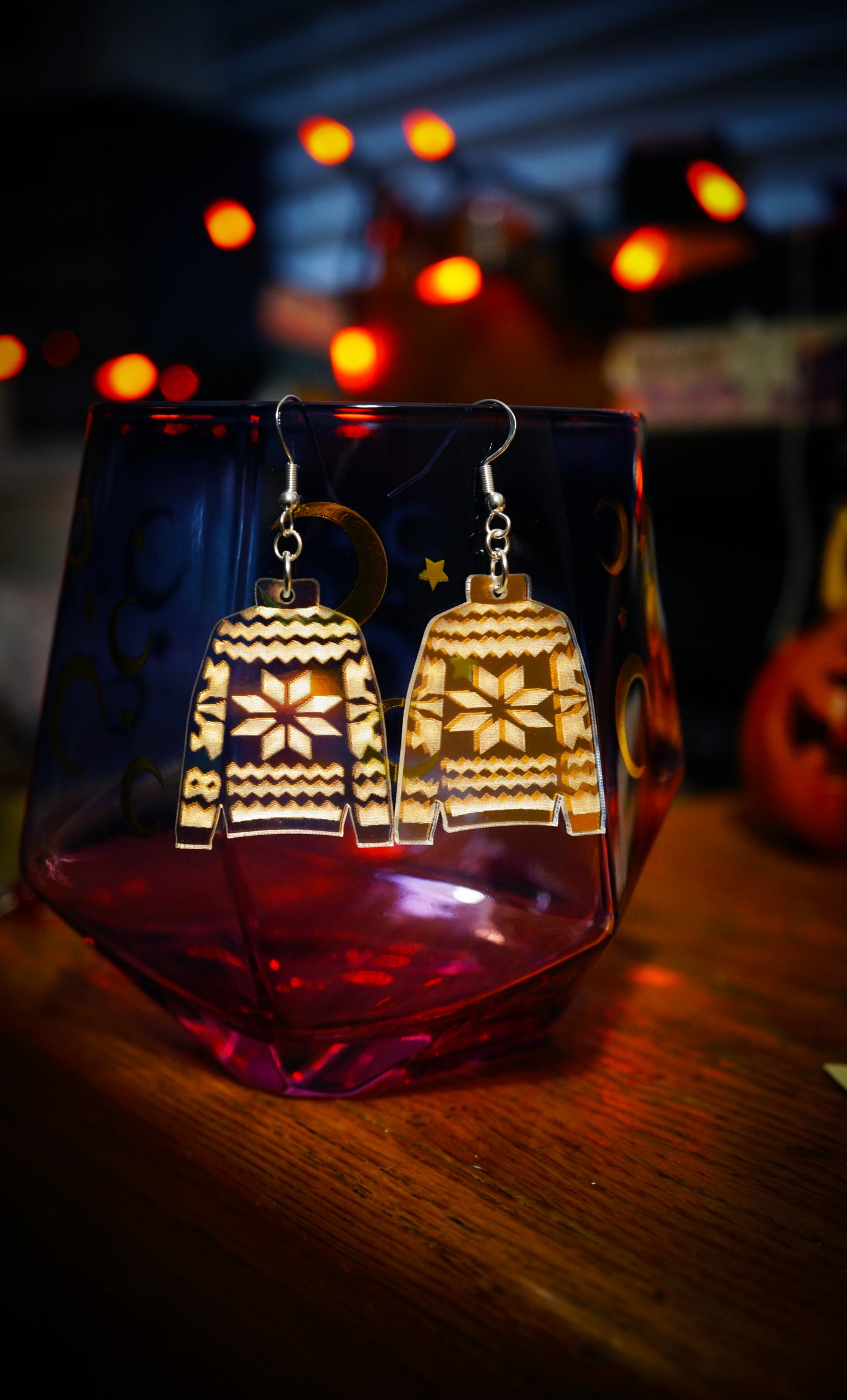 sweater weather earrings on magical cup, christmas lights in background