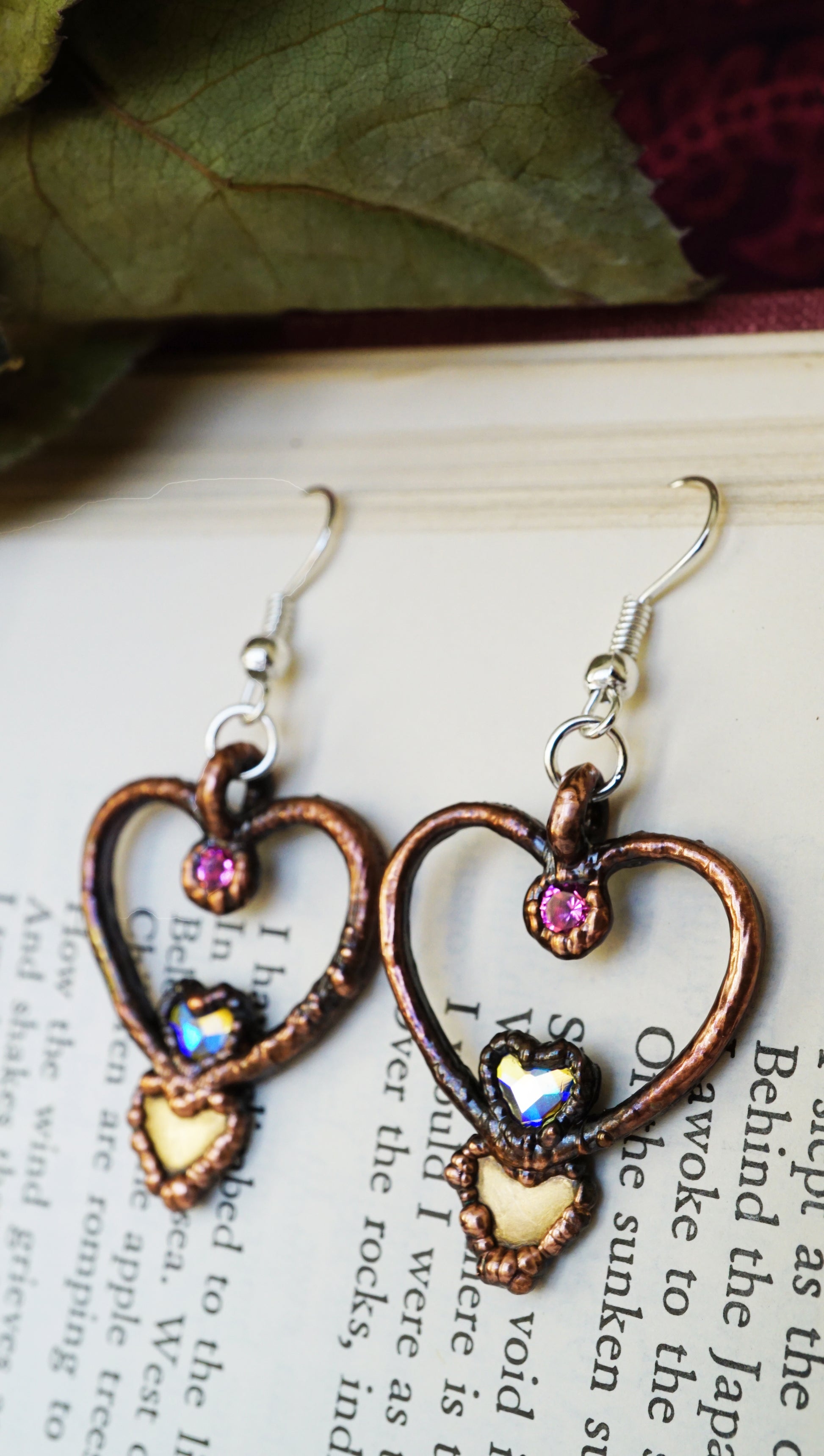 Heart-shaped earrings with pink gemstones on a book page