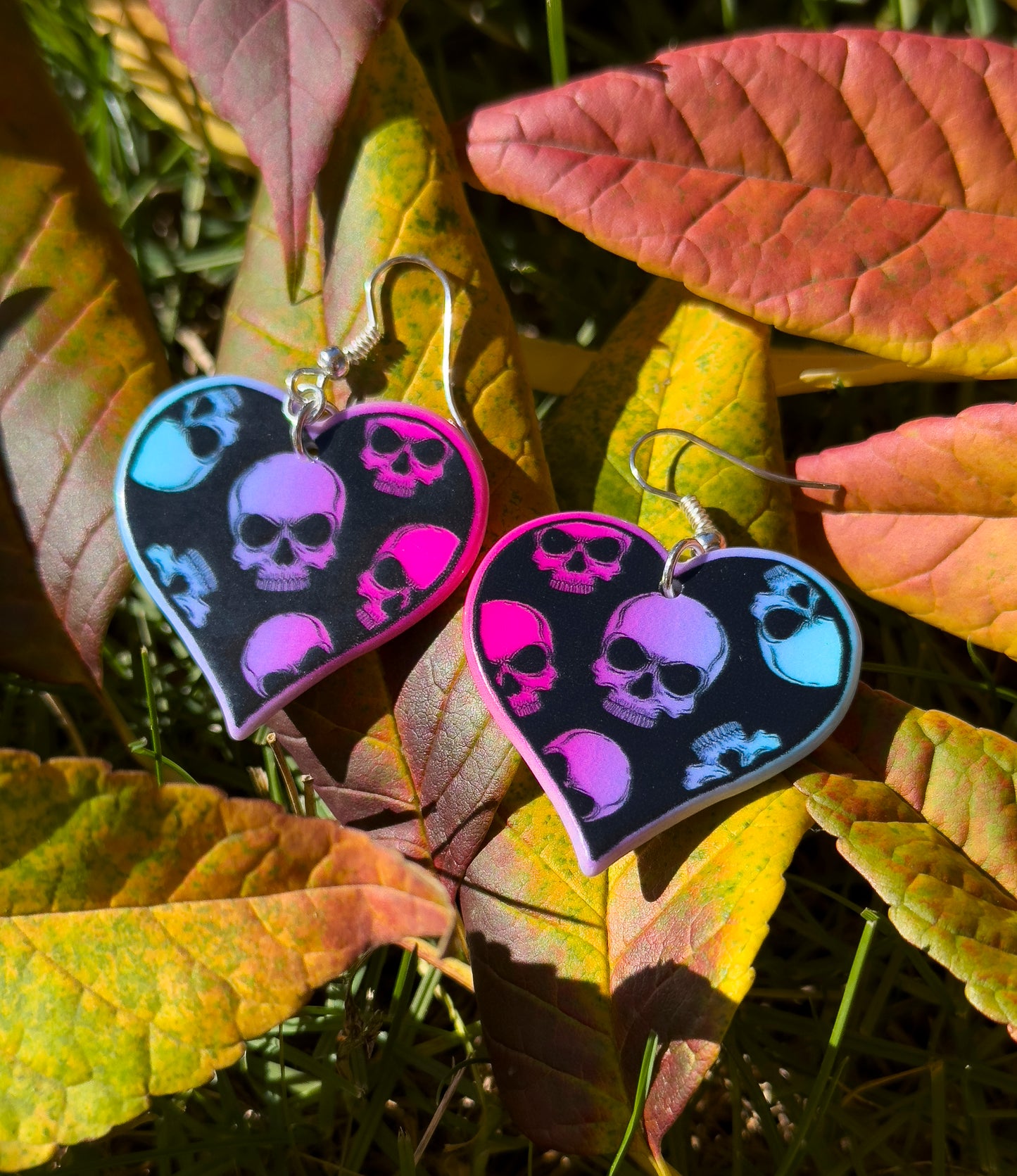 Heart-shaped earrings with skull design on Fall leaf background