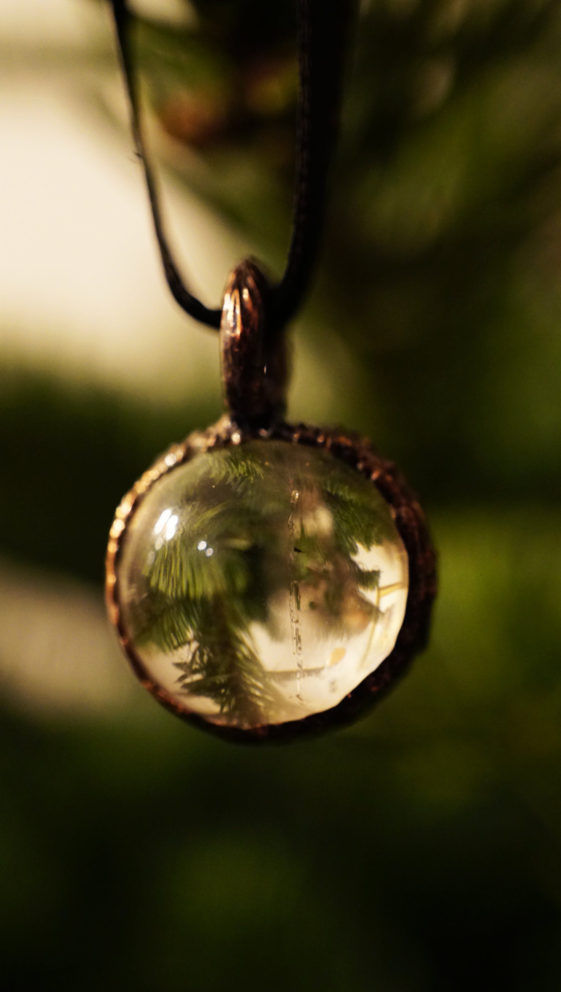 seeing green christmas tree branches through the lens of a clear quartz ornament