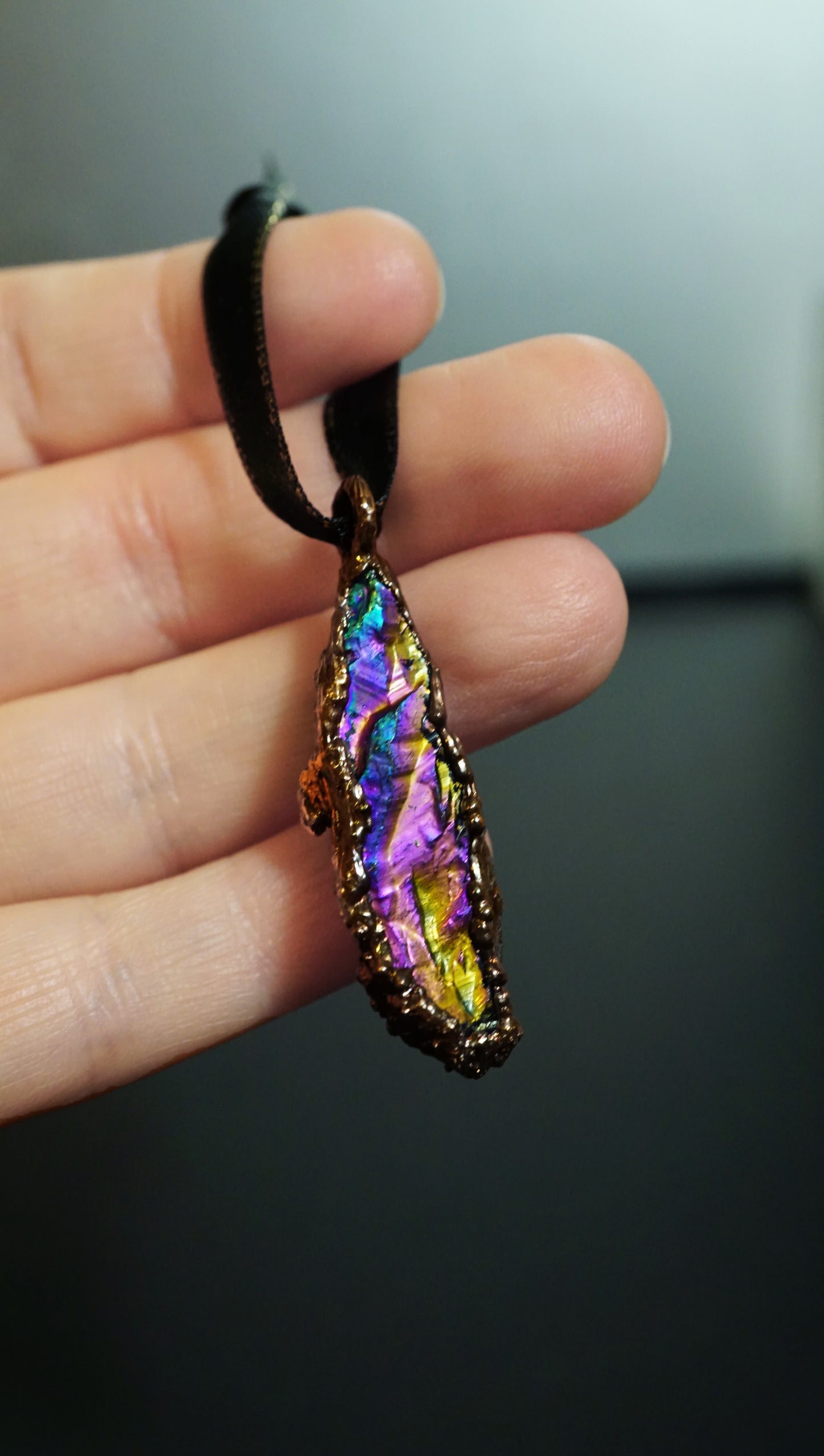 Multicolored ornament held in a hand against a dark background