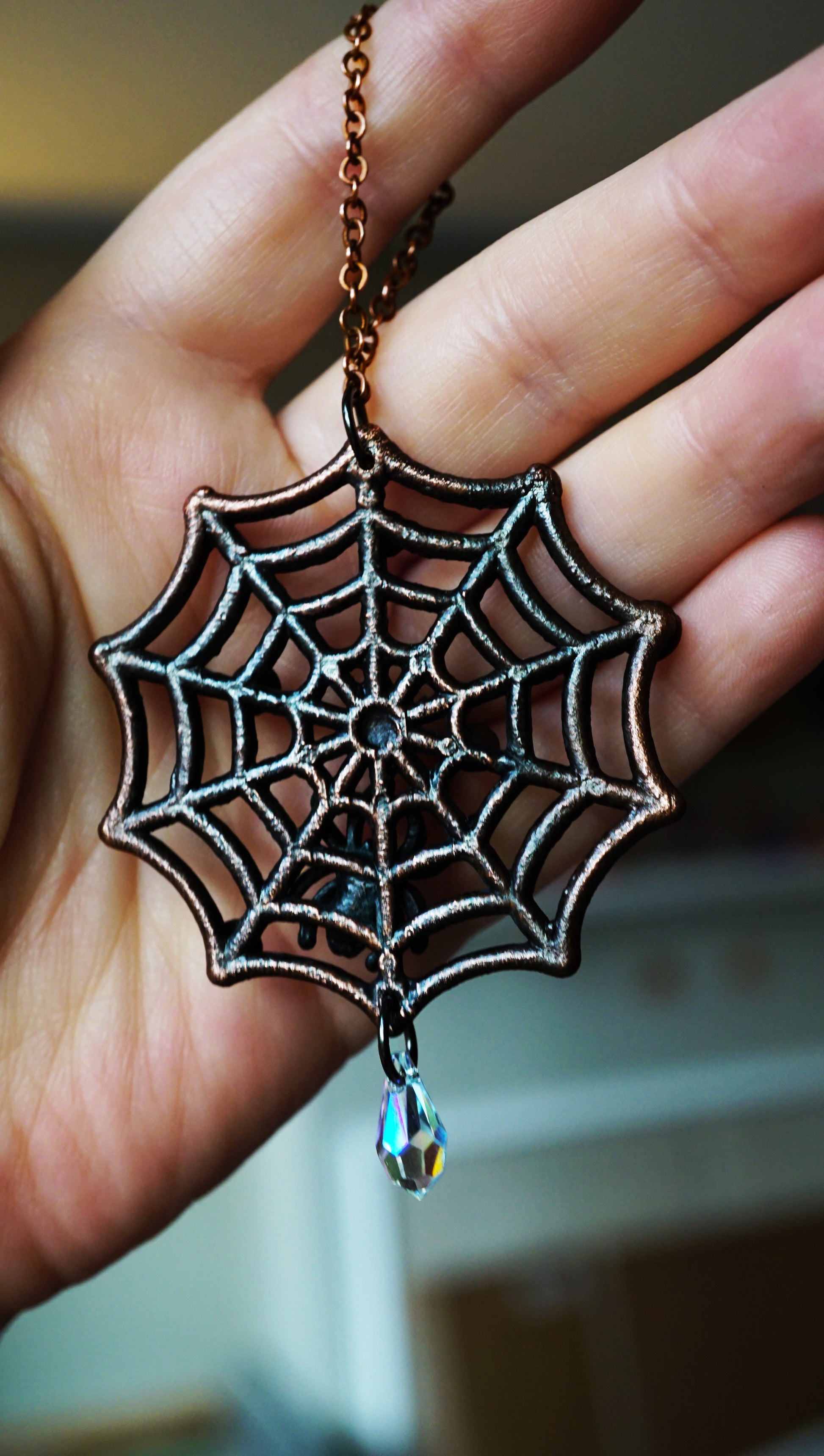 back side of Nightmare Before Christmas Spider web ornament with multicolored gemstones held in a hand.