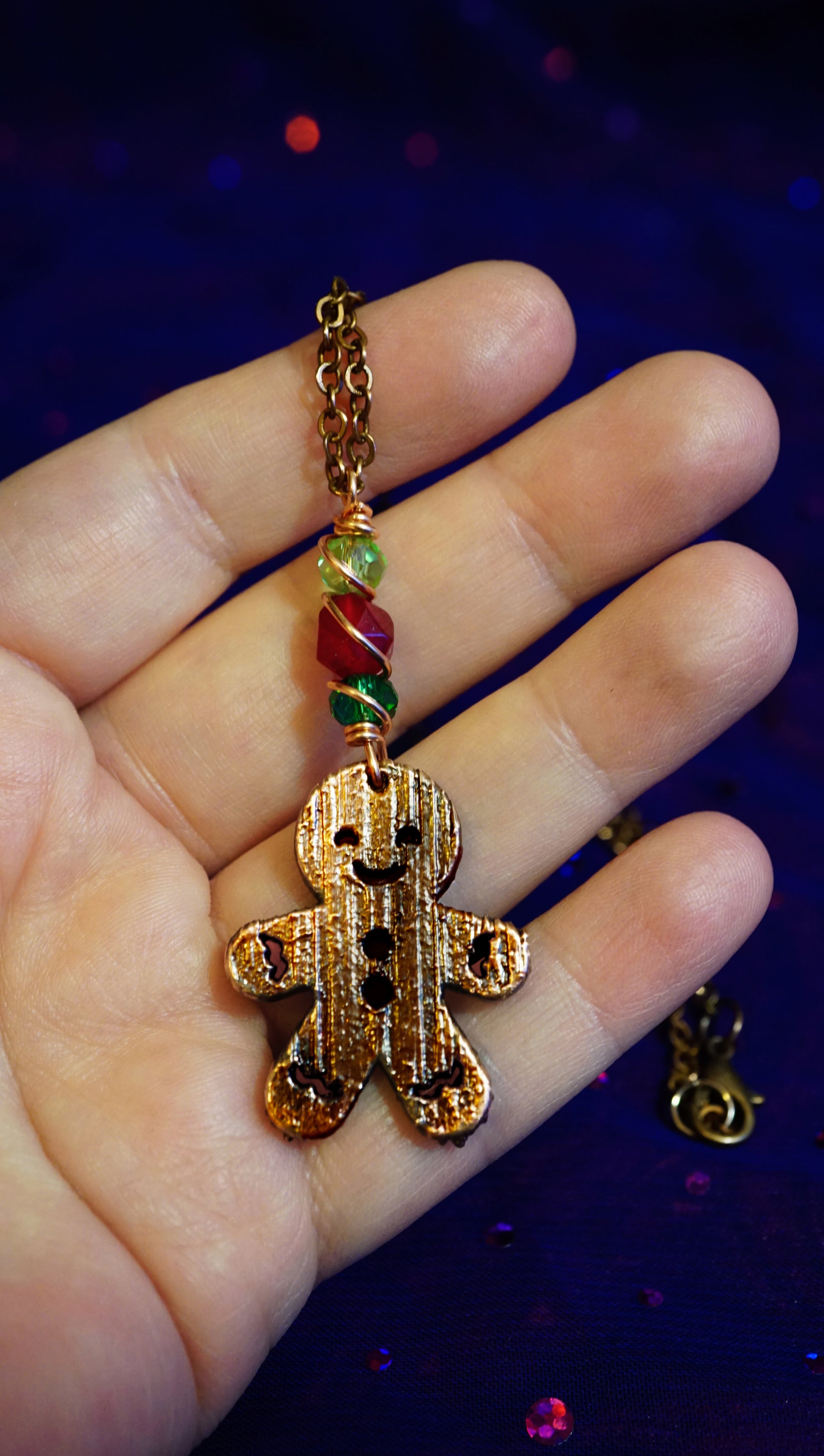 Gold gingerbread man charm on a hand with a dark blue background