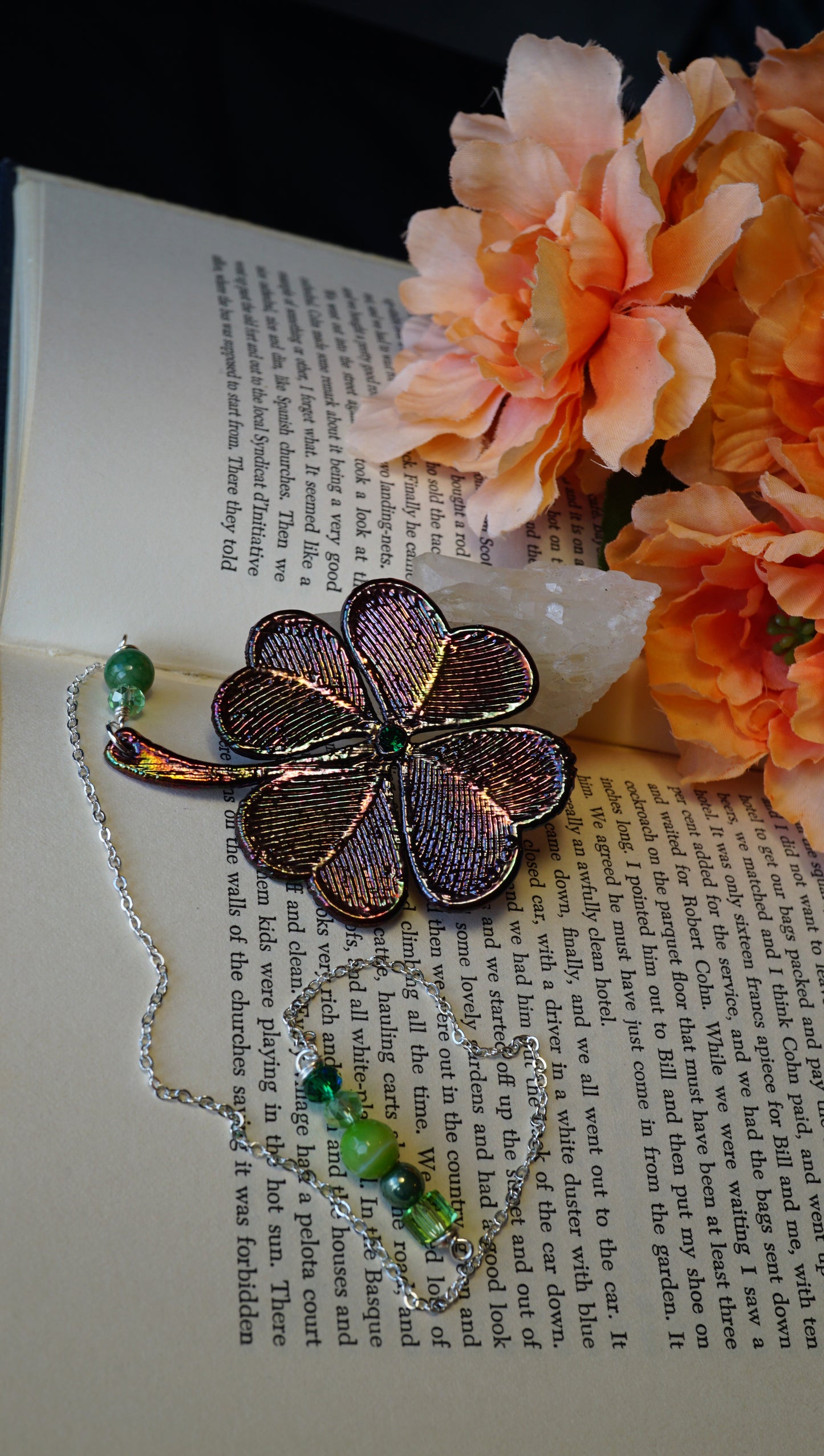 colorful metal 4 leaf shamrock wit green beads, bookmark on page with peach toned flowers