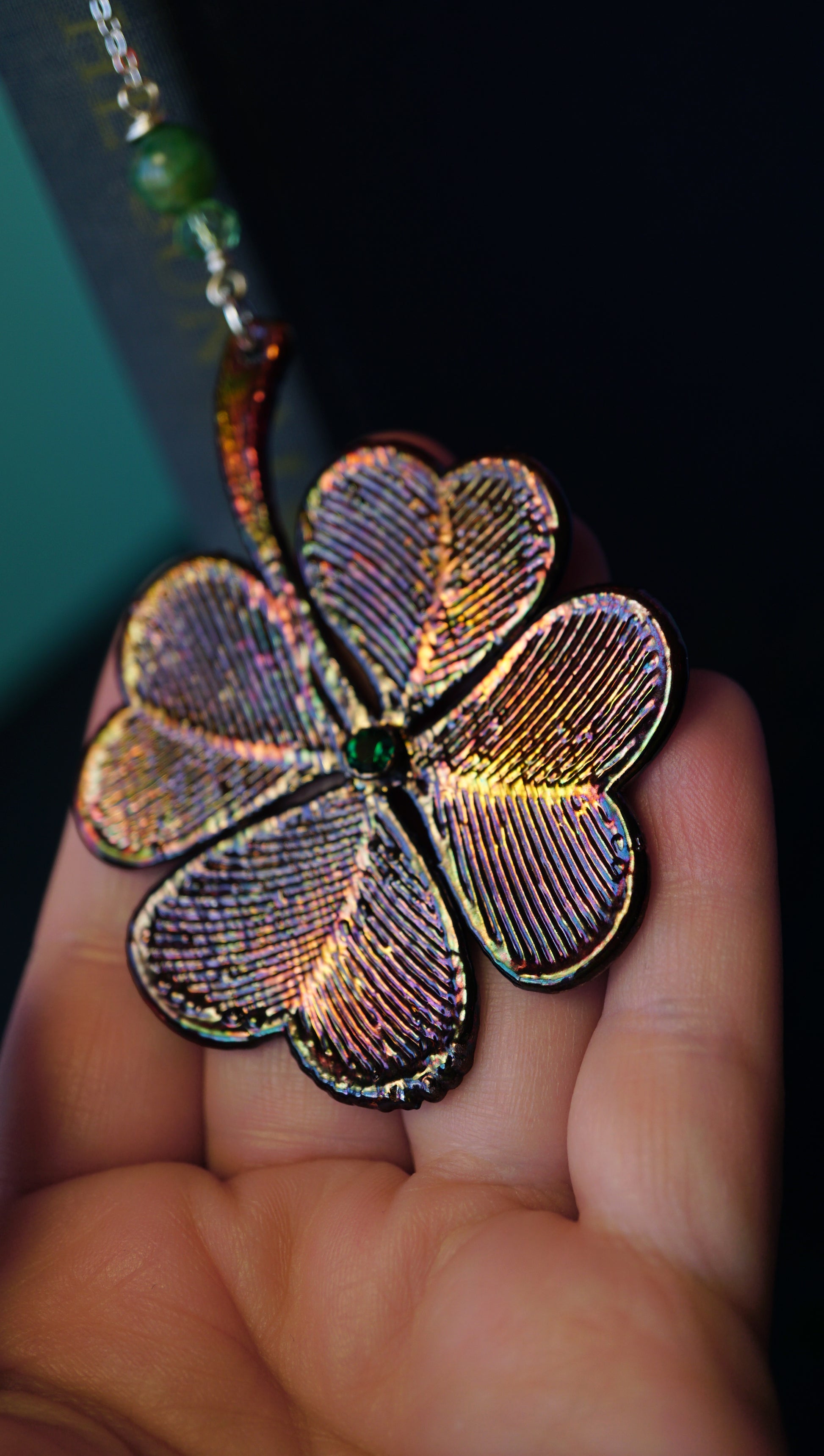 large colorful metallic 4 leaf clover bookmark with green crystal details, in hand