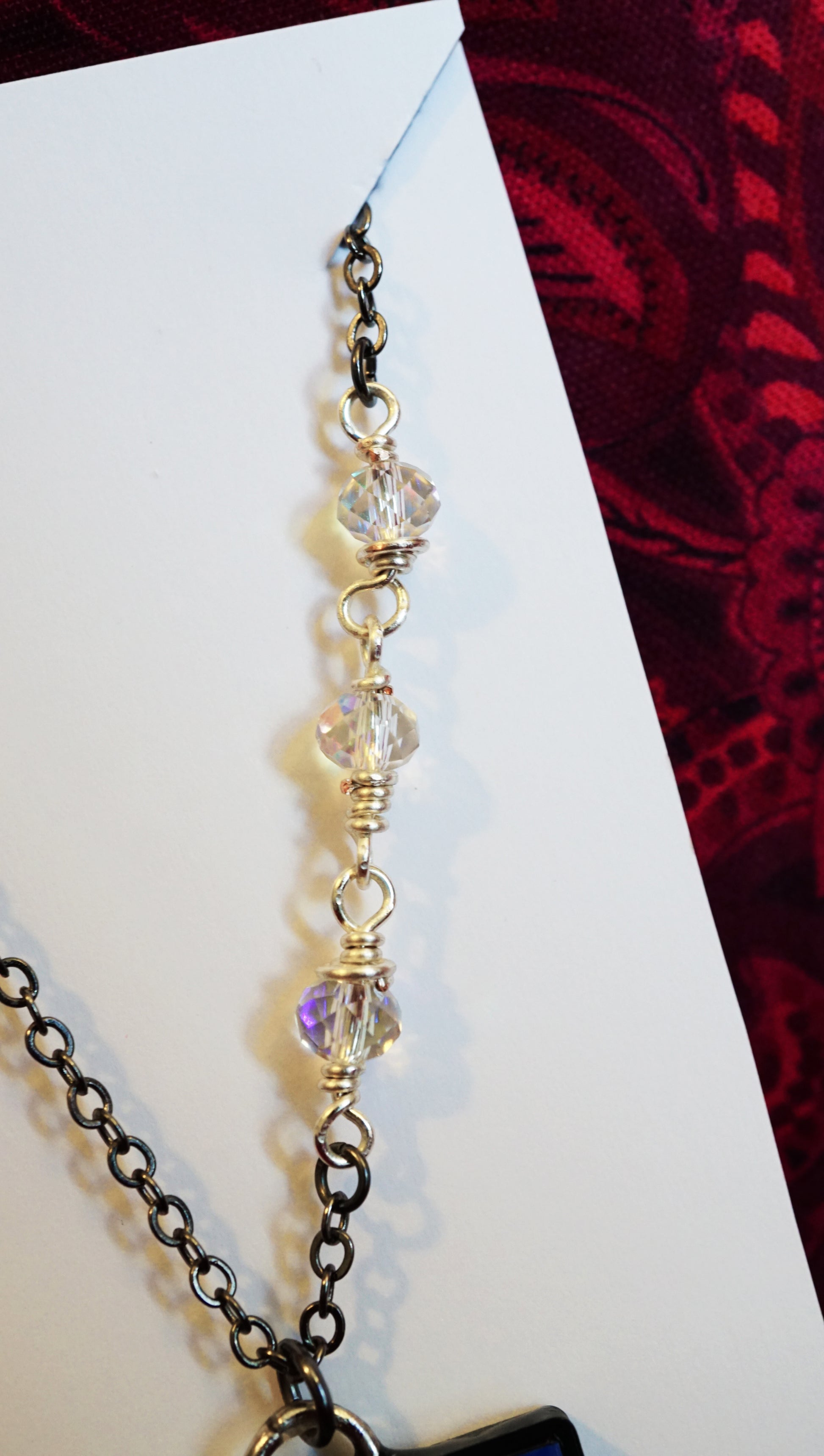 necklace with sparkly glass beads, wire wrapped onto chain, red background 