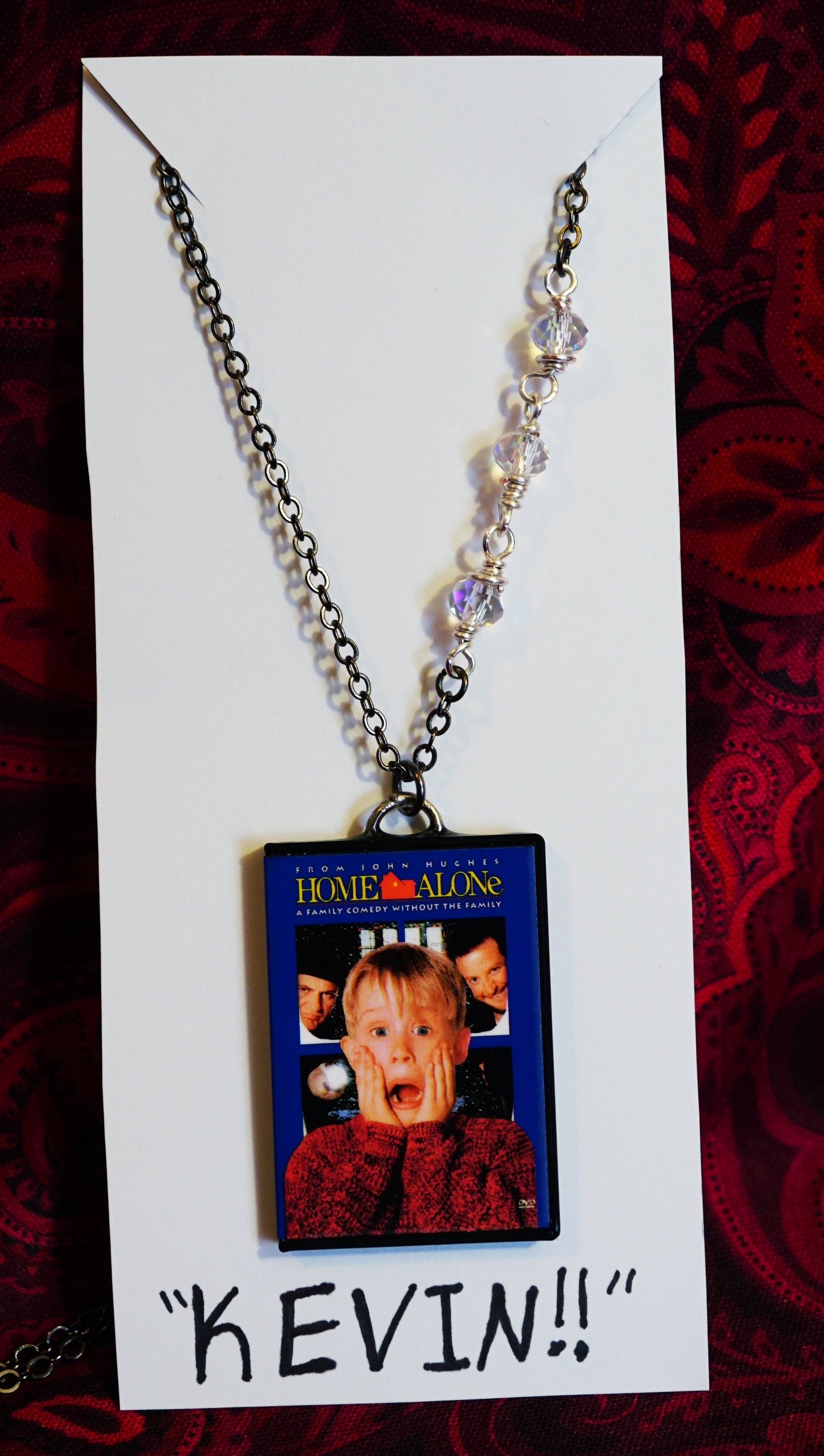 Necklace with a 'Home Alone' pendant on a red patterned background
