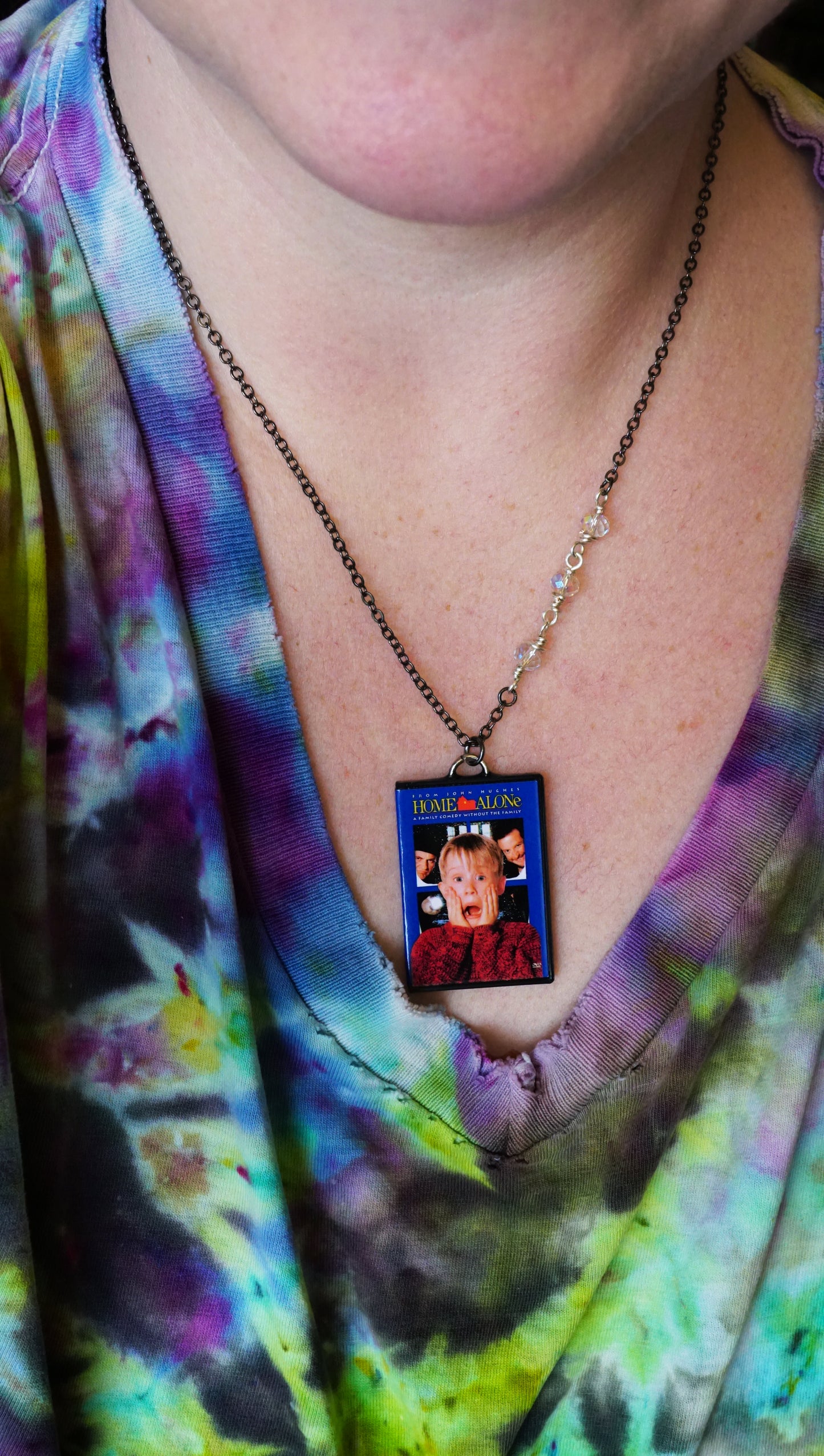 woman wearing home alone necklace with tie-dyed shirt