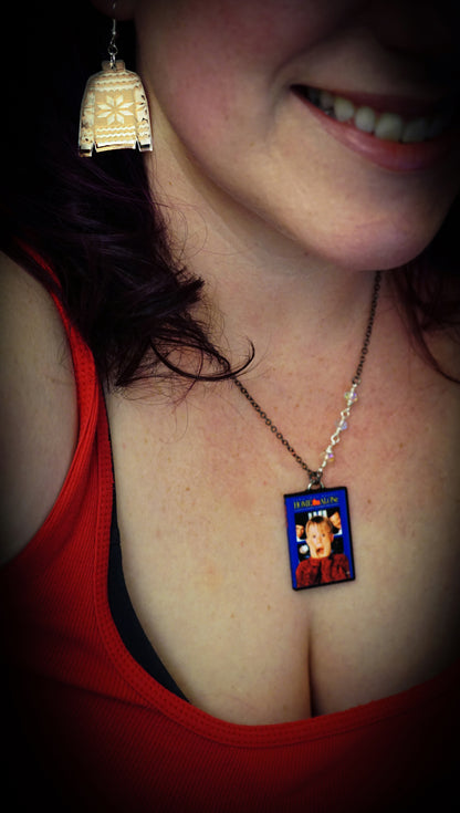 woman wearing home alone necklace and sweater earrings, red shirt