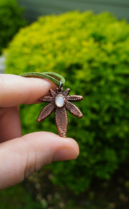 Hand holding a decorative pendant with a green blurred background