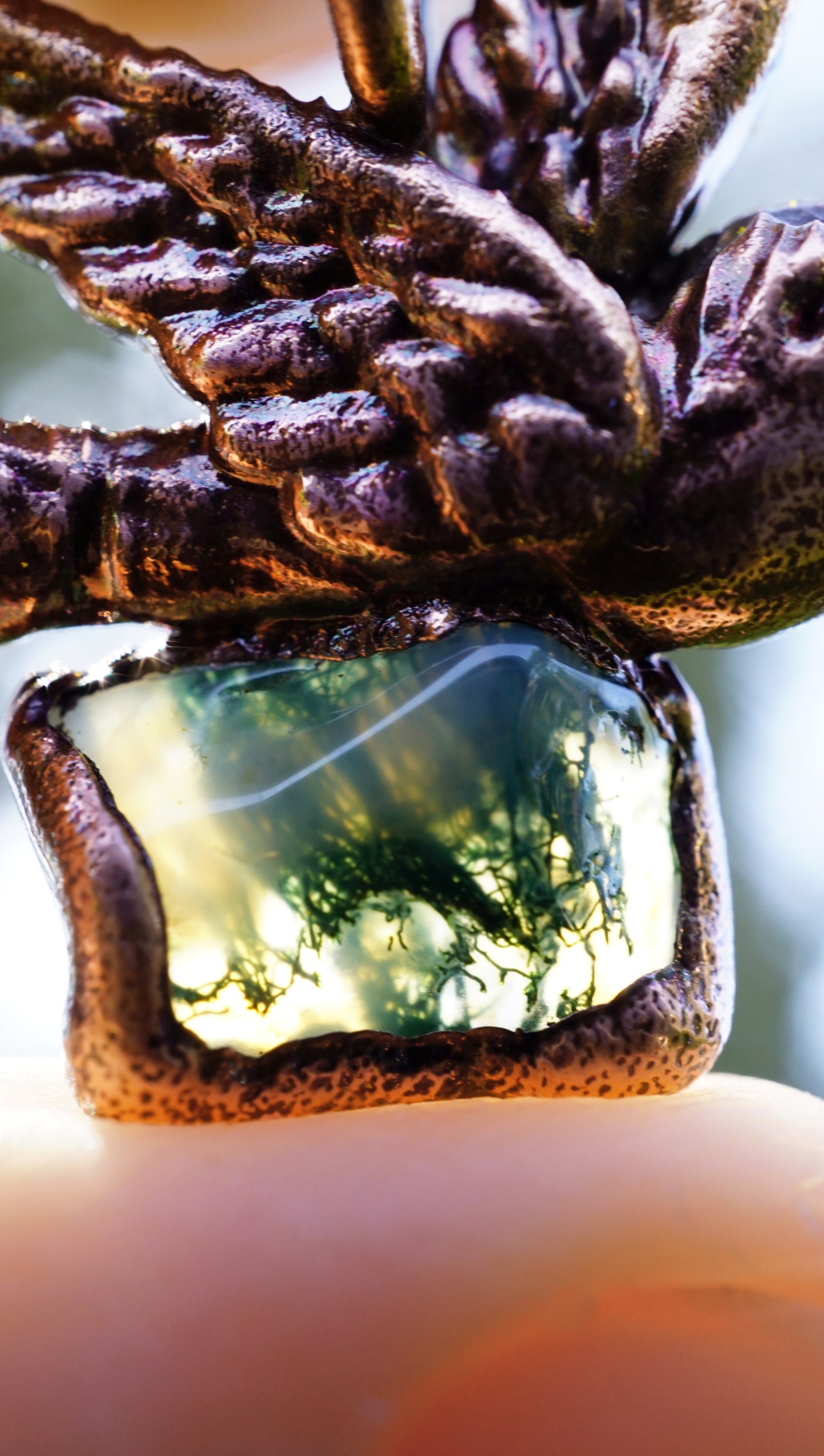 close up of green mossy inclusion stone within a copper sparrow pendant setting, it glows in the sunlight