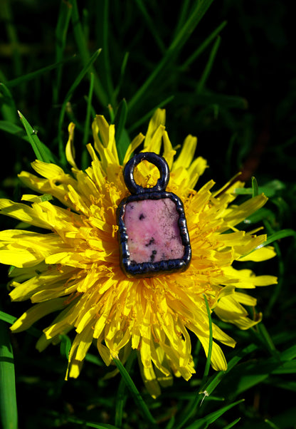 Pink stone pendant on a yellow dandelion flower