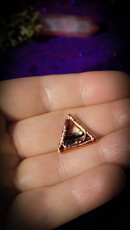 light copper triangle with dark green moss gate in center, in hands, with purple background
