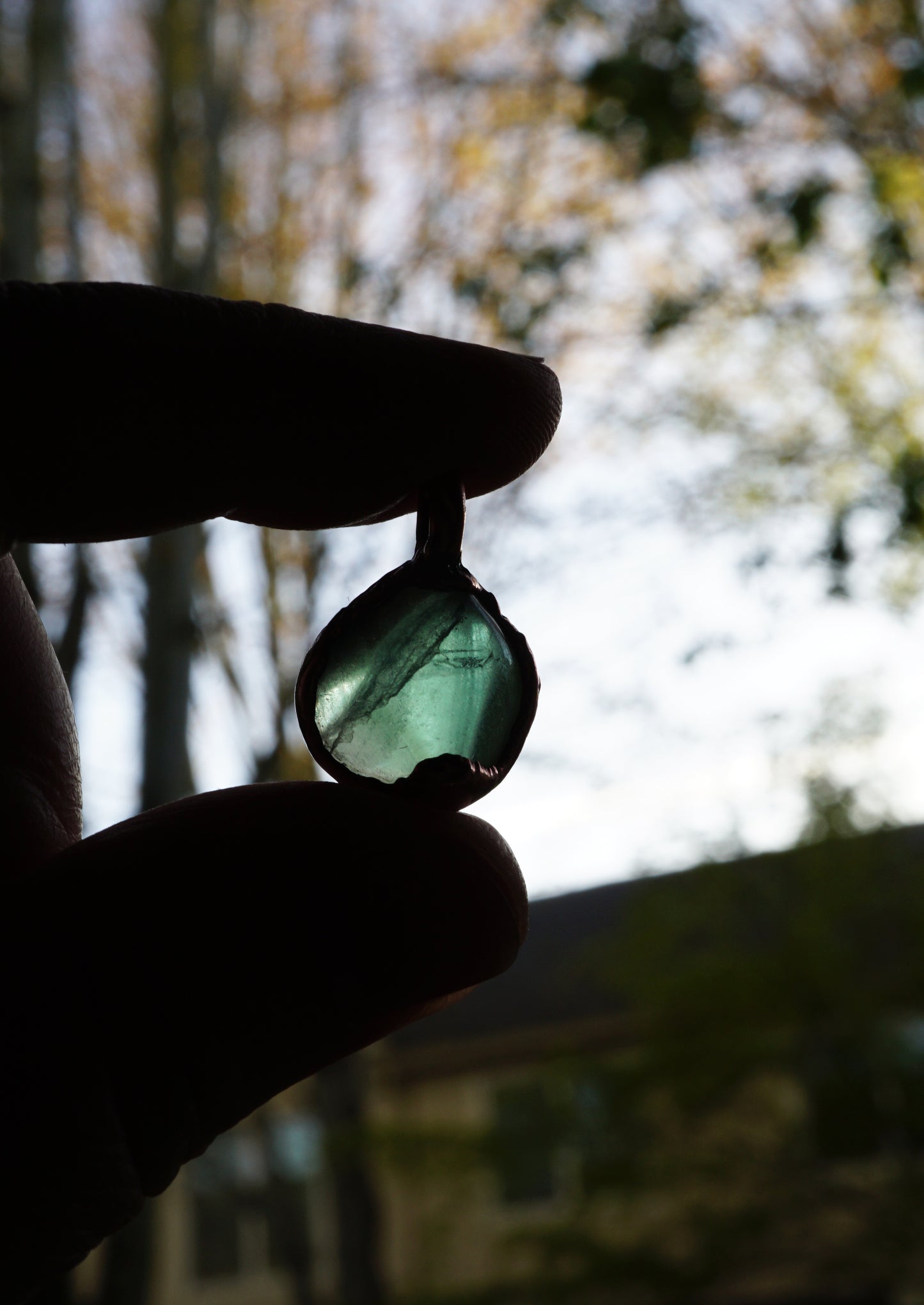 Person holding a green stone with a blurred natural background