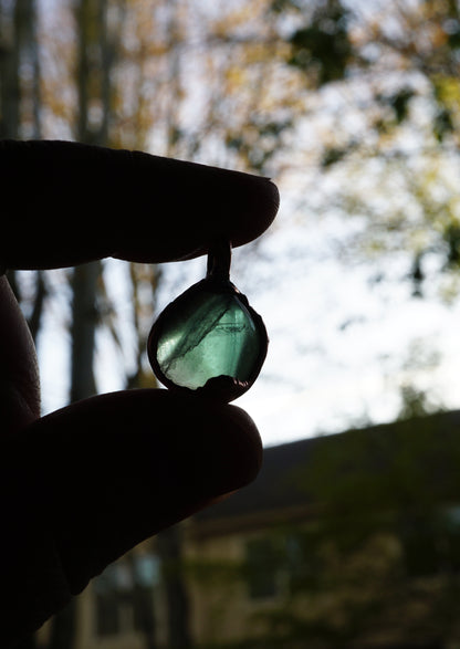 Person holding a green stone with a blurred natural background