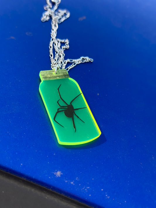 Neon green pendant with spider design on a blue surface